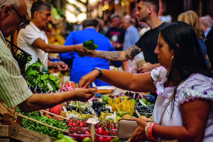 People handing money to shop keepers at food market